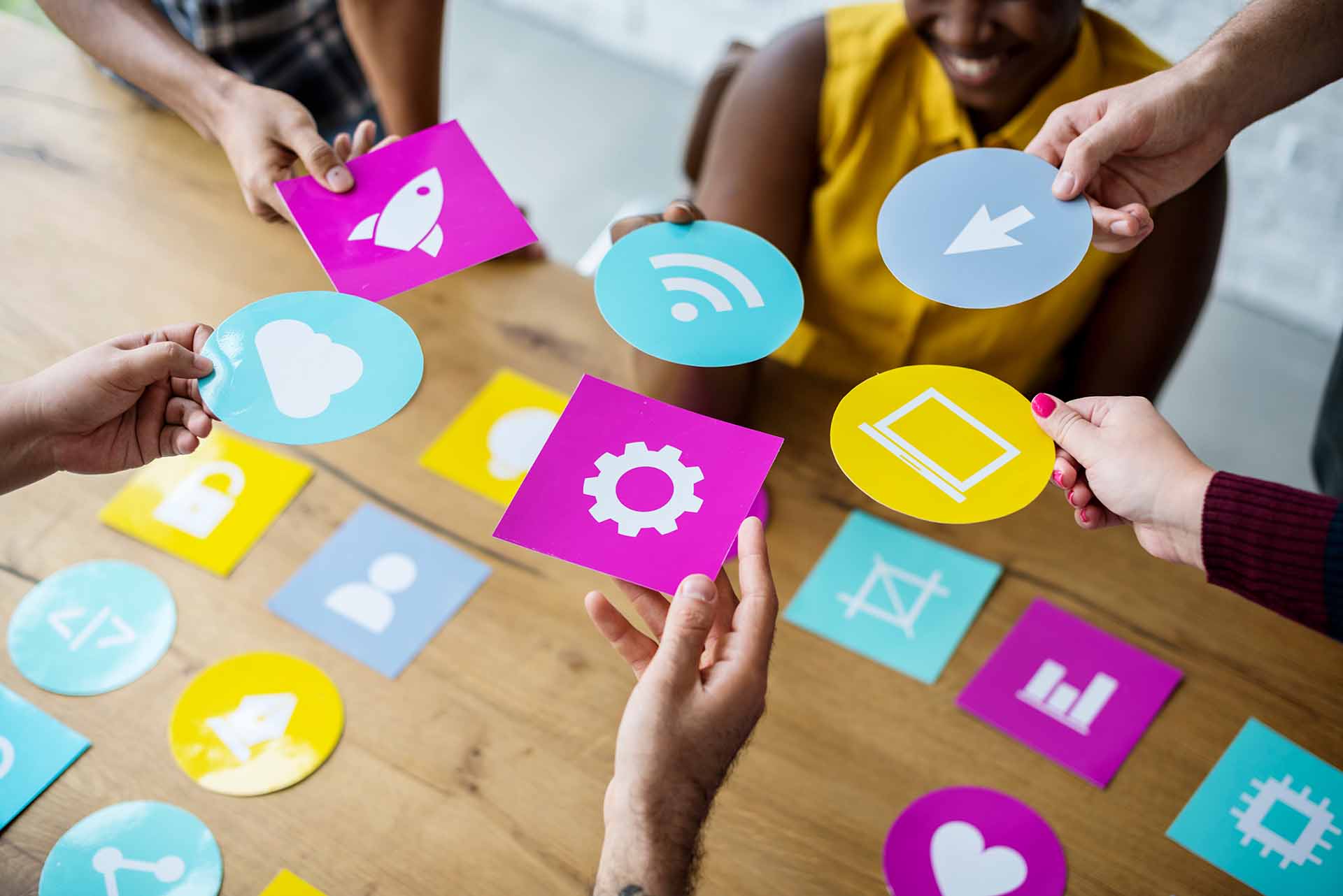 Group of people collaborating with colorful icon cards representing various online and digital marketing elements.