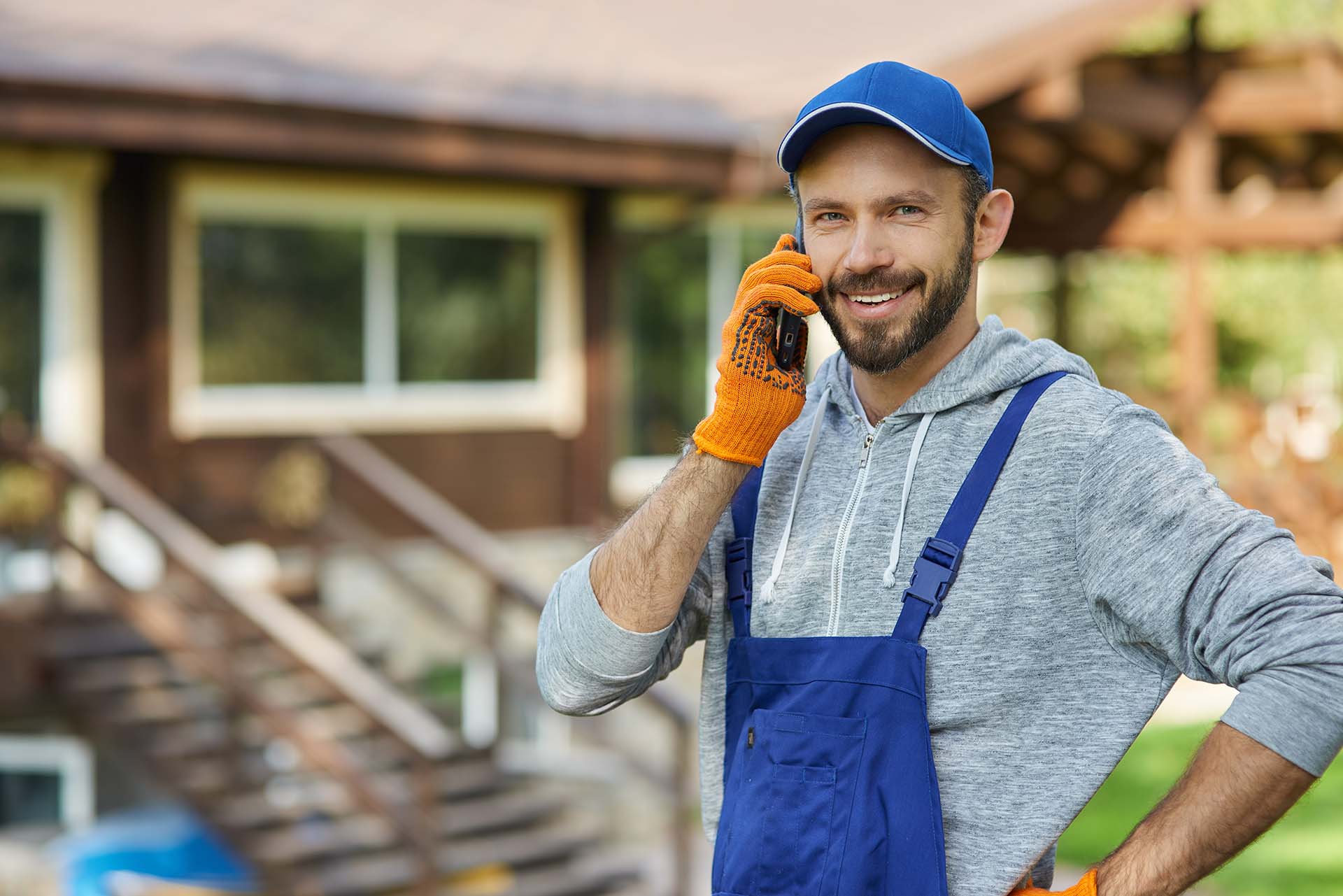 Smiling male builder in uniform making a phone call, symbolizing excellent customer service in landscaping companies.