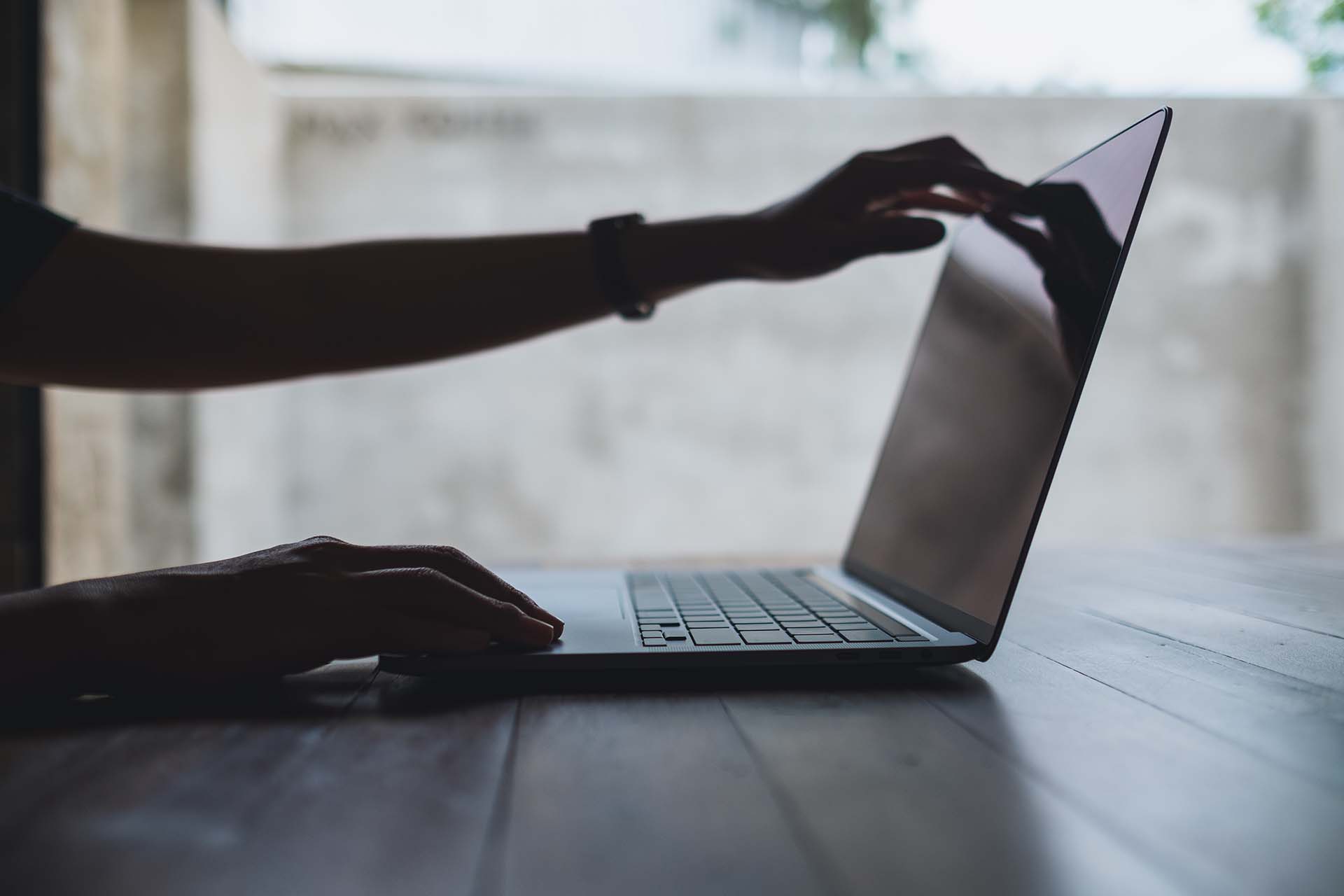 A hand opening a laptop, ready to use the best app for scheduling and routing in a landscaping business.