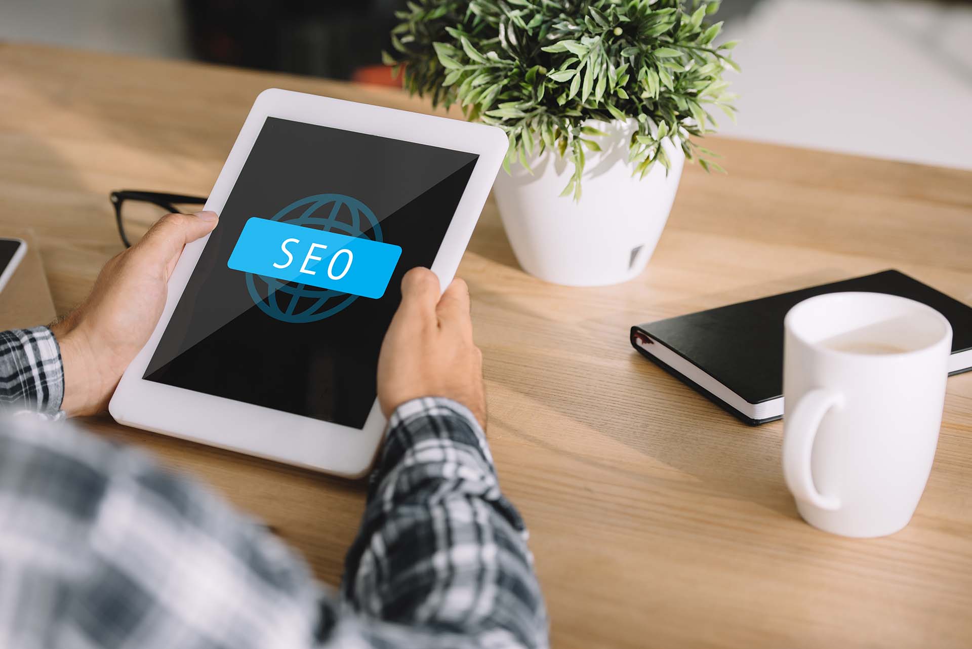 A person holding a tablet displaying an SEO symbol, symbolizing digital marketing for landscaping businesses.