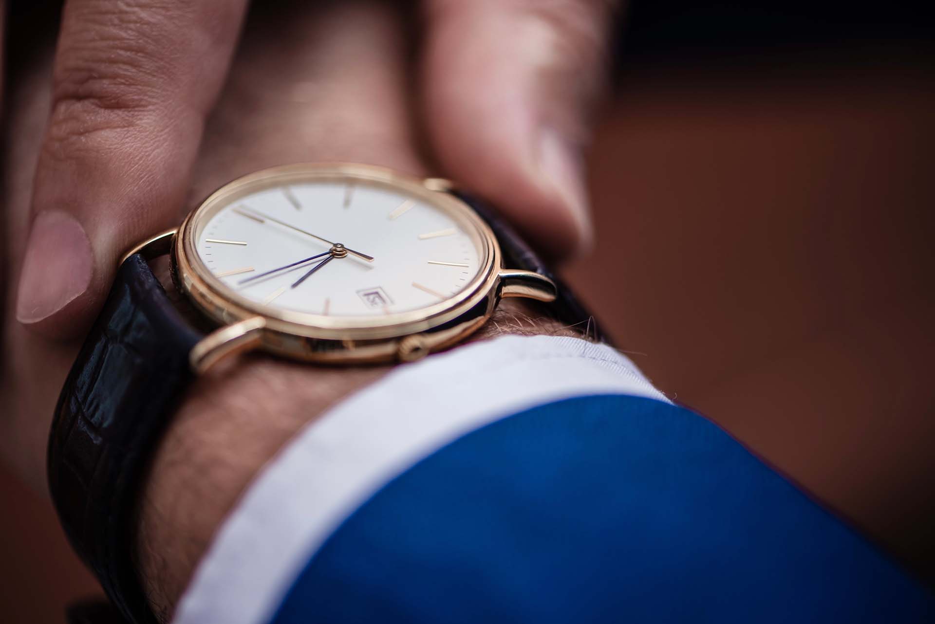 A man in a suit checking his watch, symbolizing time management strategies.