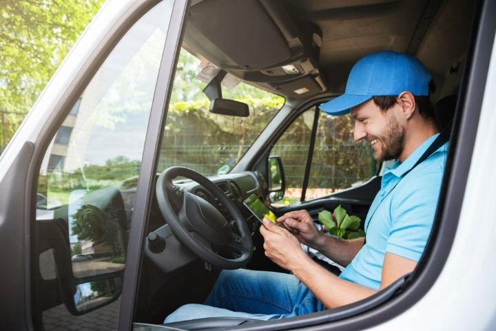 Smiling landscaper using tablet in work van to manage bookings or schedule