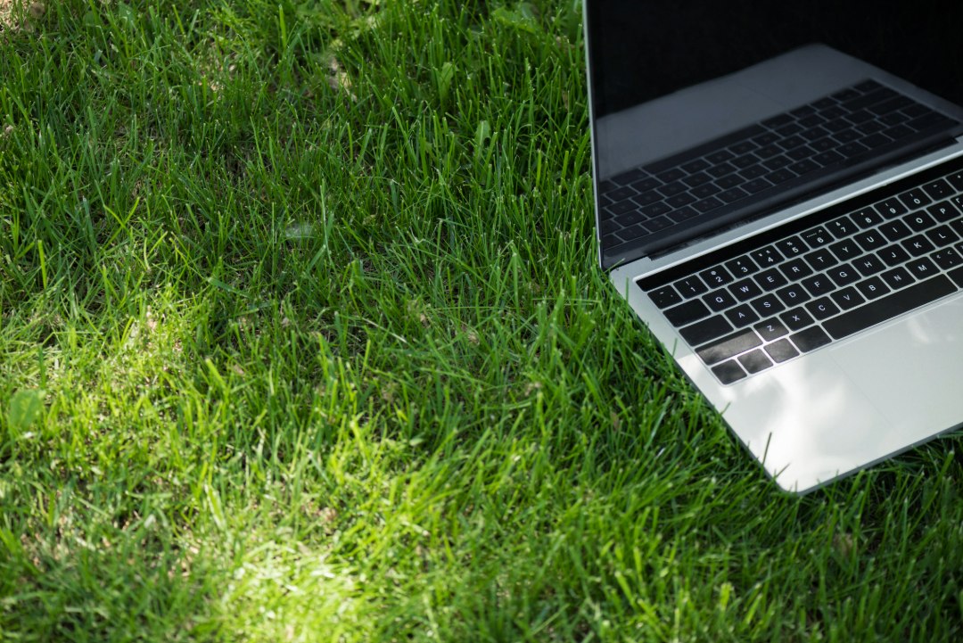 laptop resting on fresh green grass, symbolizing outdoor work or digital tools for landscaping businesses