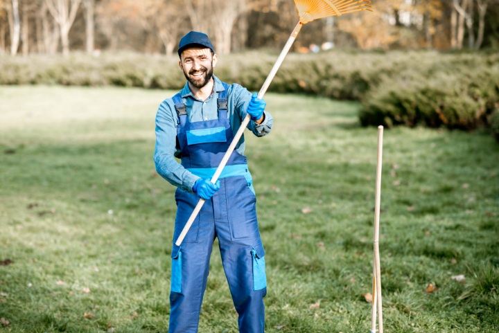 Smiling Lawn Care Worker Holding a Rake During Spring Yard Cleanup