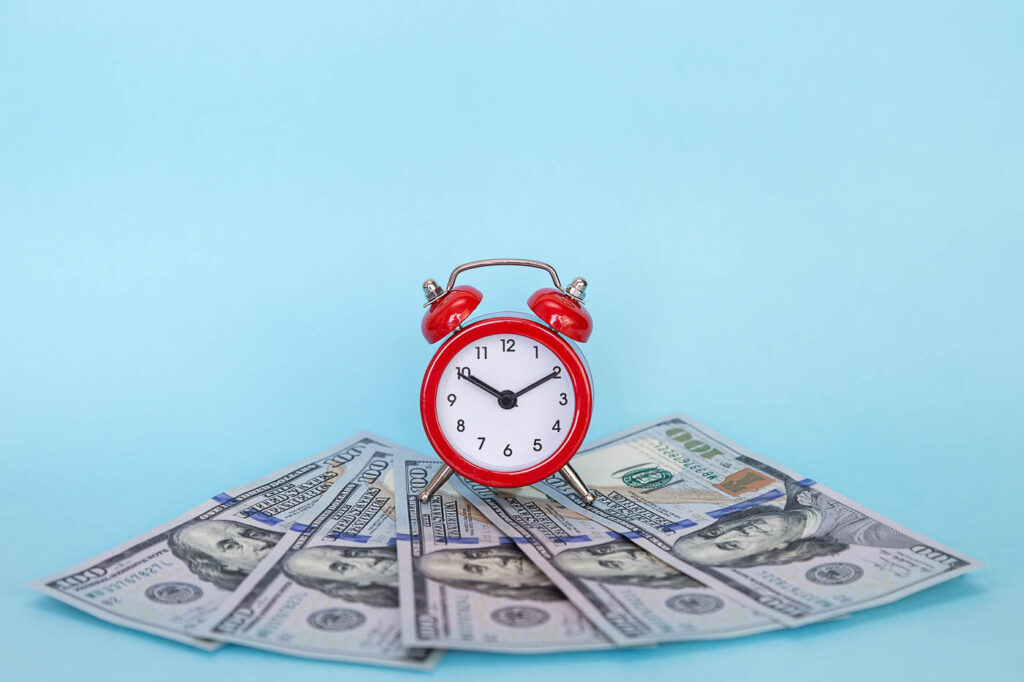 Red Alarm Clock On Money Representing Time And Profit