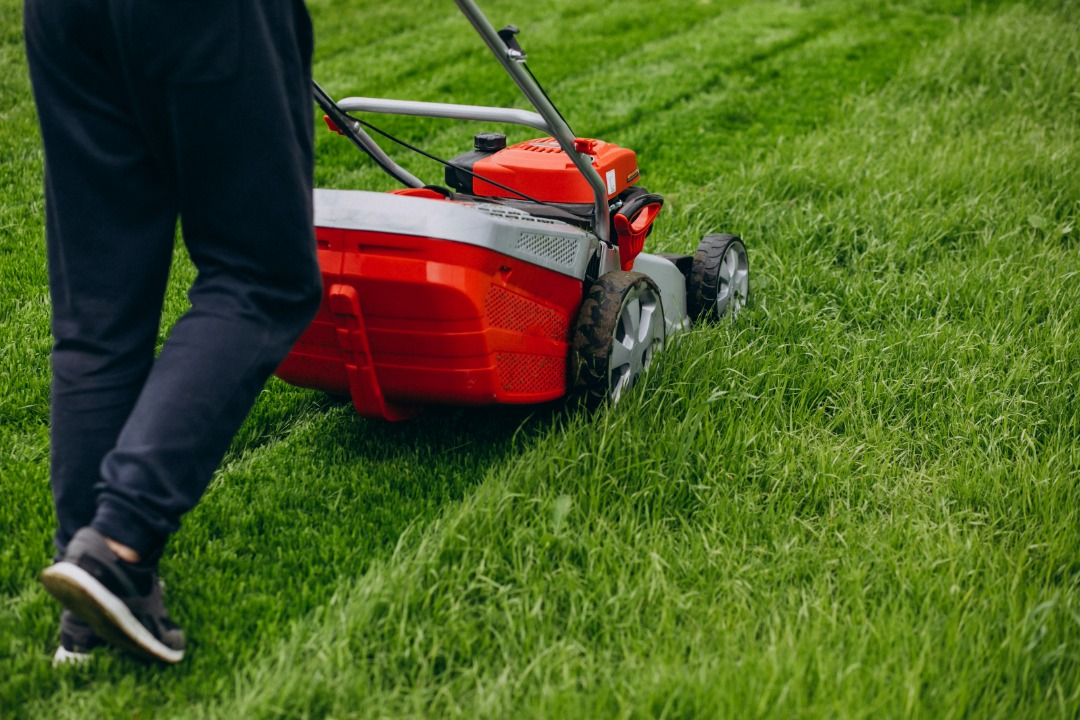 landscaoer cutting grass with a lawn mower