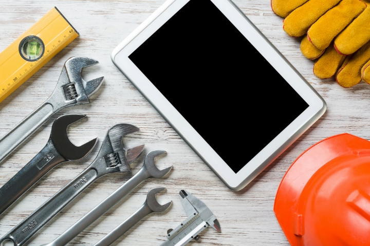 Tablet With Digital Screen Surrounded By Construction Tools, Safety Helmet, And Gloves