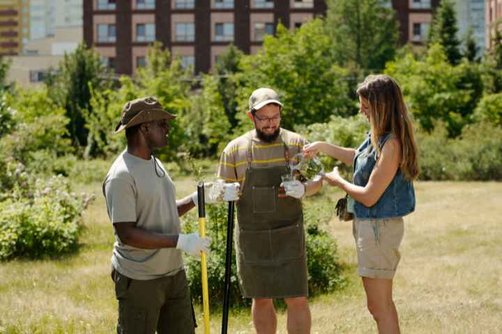 Three Landscapers Taking A Water Break In The Field With Landscaping Tools