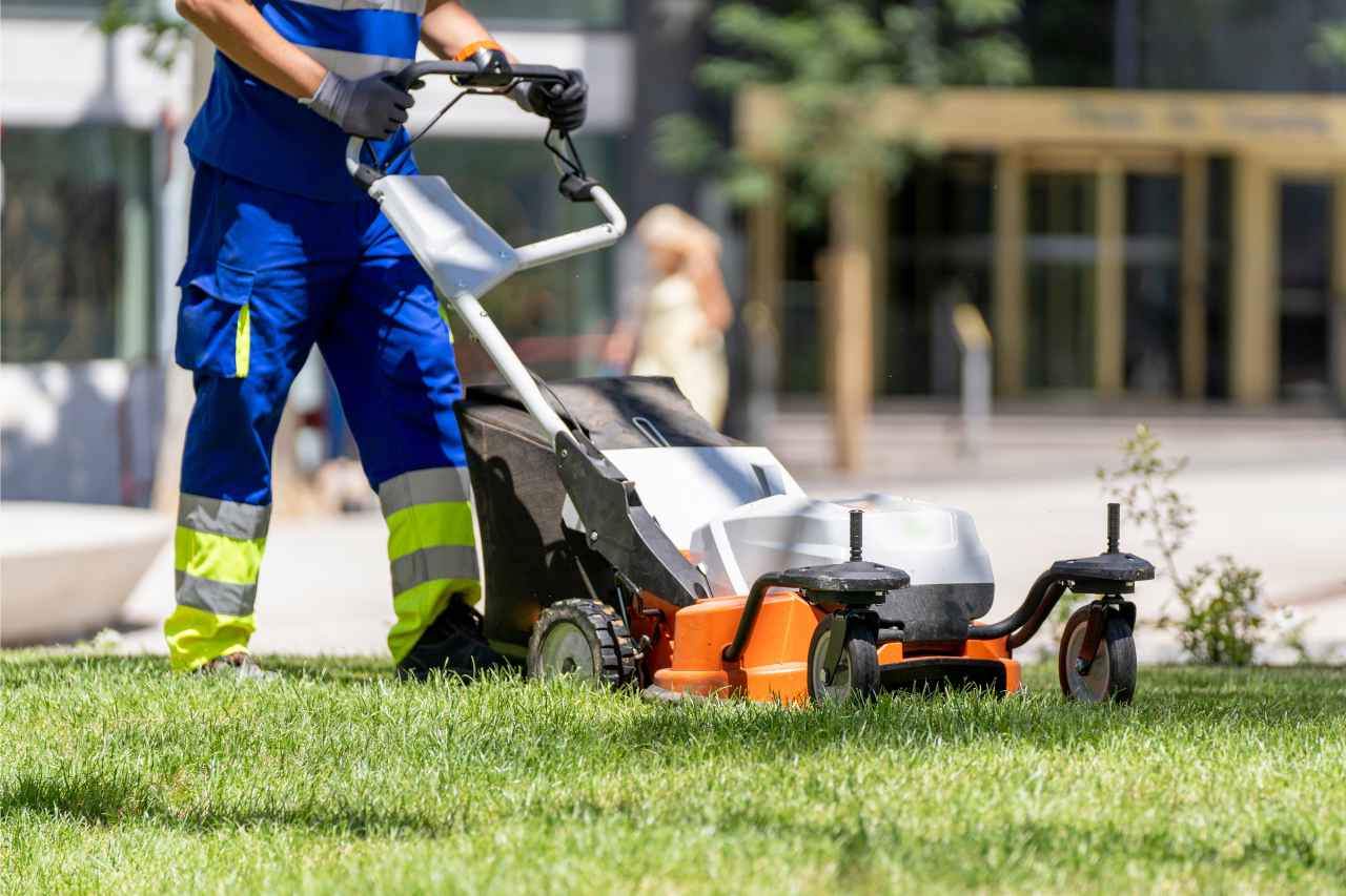 Man Mowing Green Lawn In An Urban Setting